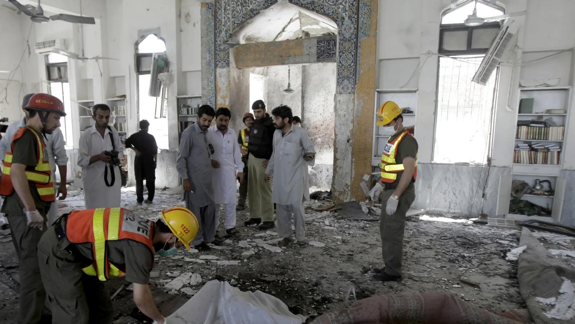 Scene outside a bombed mosque in Pakistan with rescue workers and damaged structure