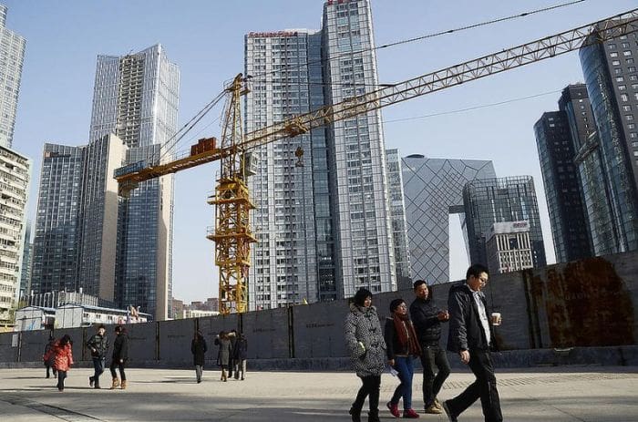 A dim, nearly empty construction site in China with idle cranes and unfinished buildings, symbolizing the investment crash and rising credit risks across the economy.